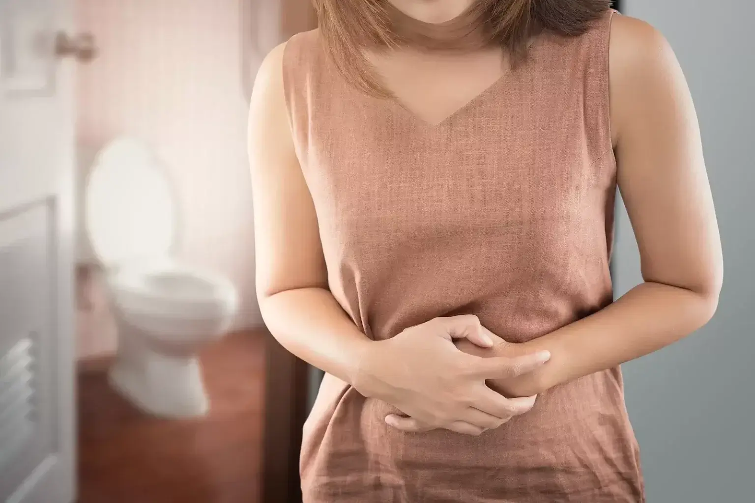 Toaletná misa s riedkou, vodnatou stolicou a pohárom vody vedľa, znázorňujúca typický príznak hnačky a dôležitosť hydratácie.